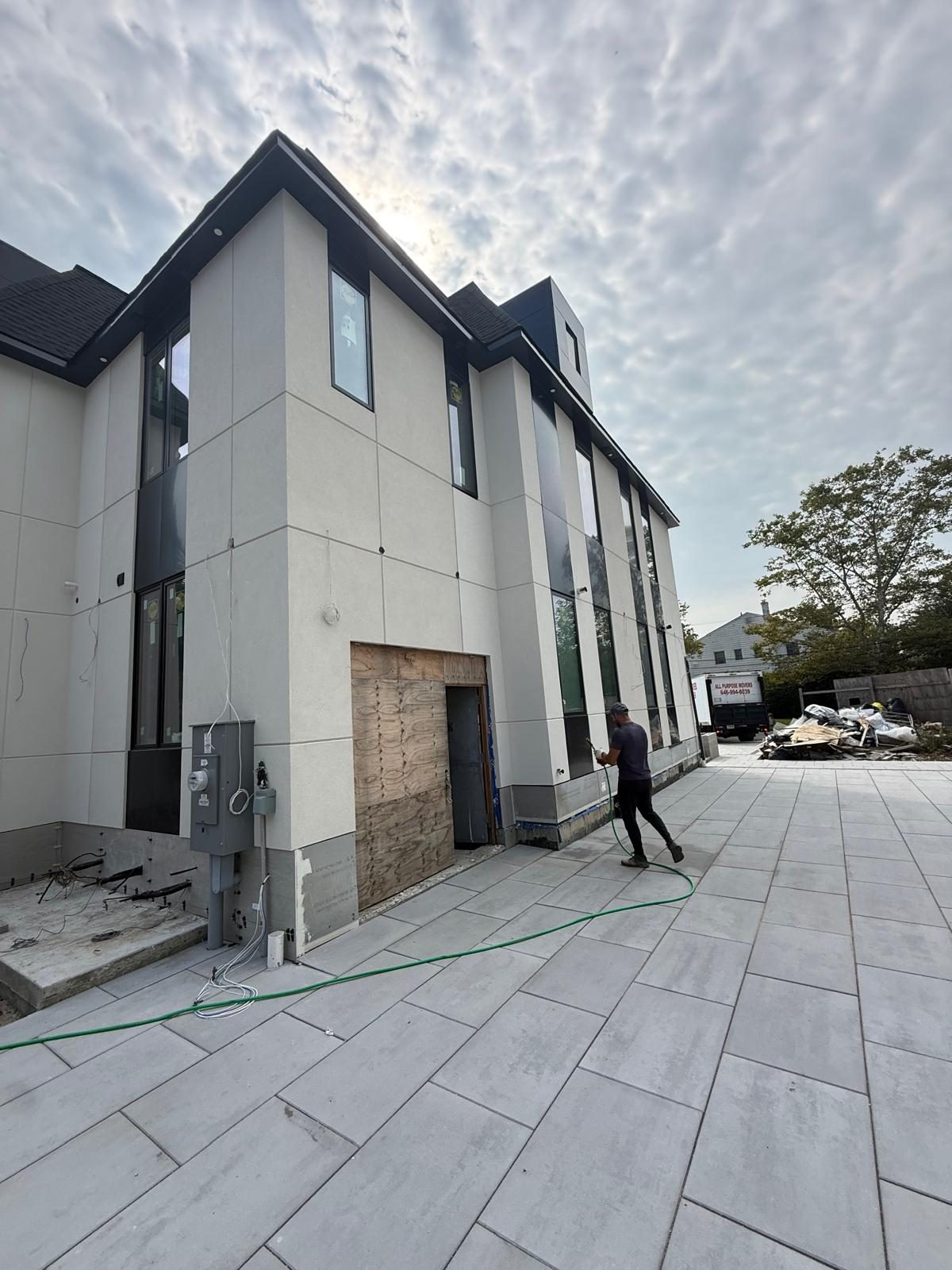 Side elevation of the Woodmere custom house with Henry Blueskin air barrier exposed at the base, black ACM panel bands and Pella windows