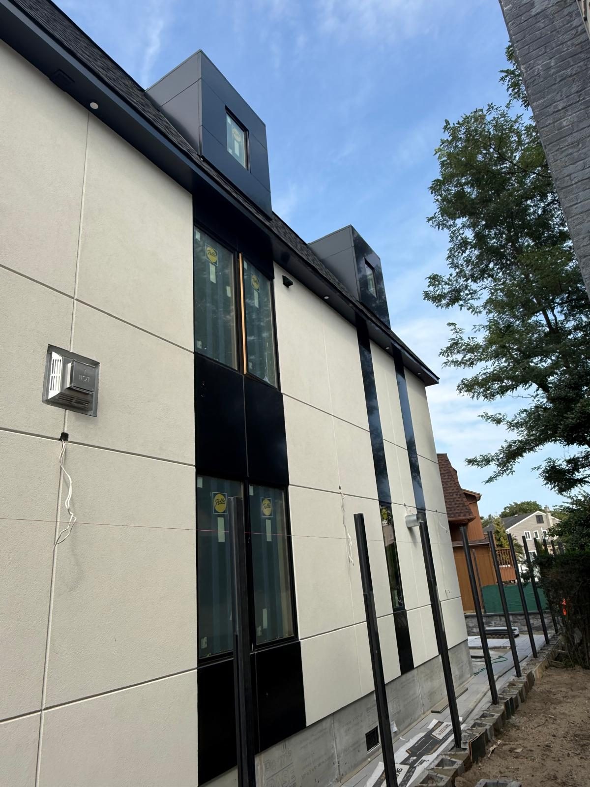 Side elevation with vertical black ACM panel bands and dormer windows above, Woodmere custom house