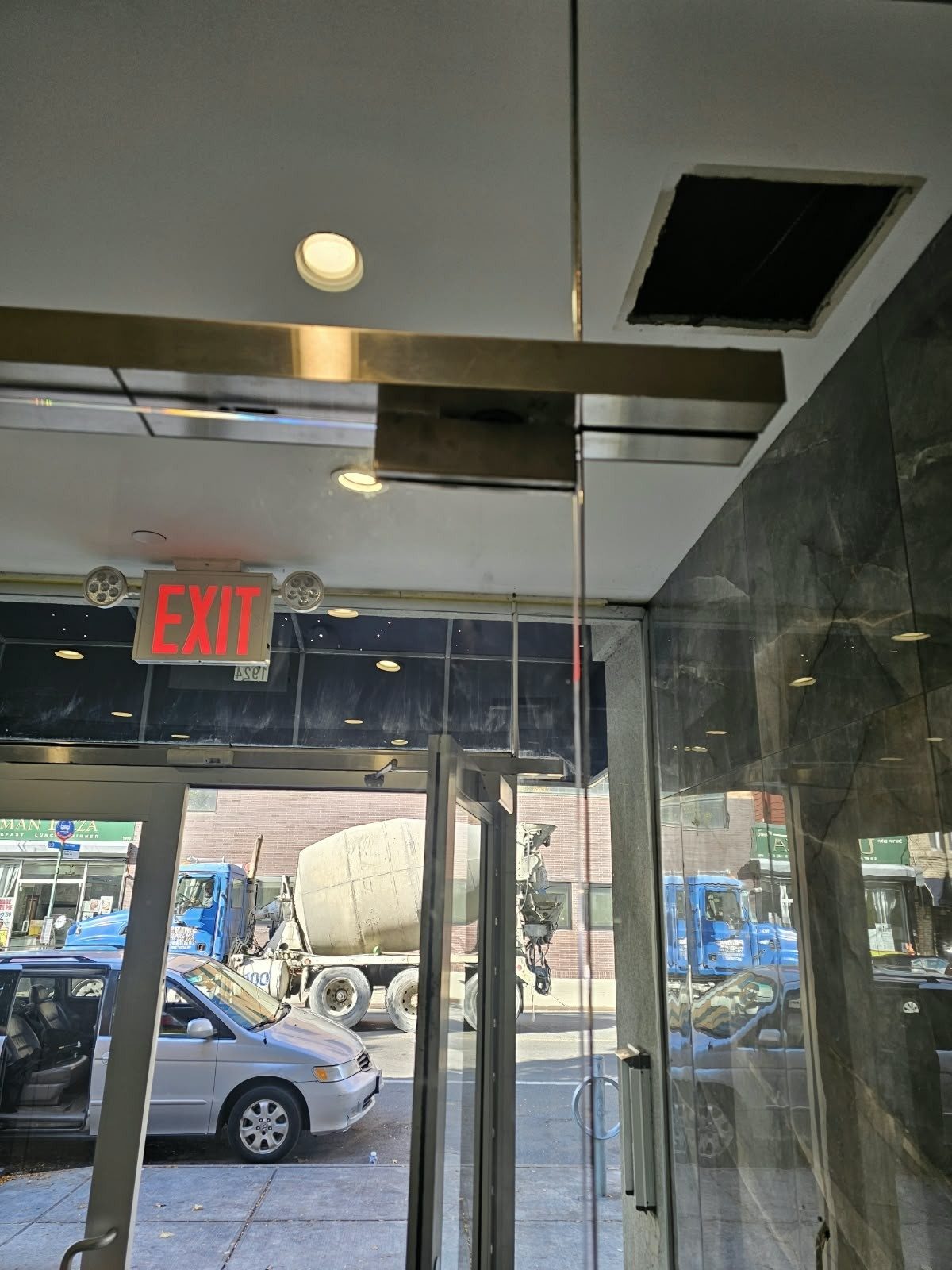 Top patch fitting and overhead closer header on a frameless glass lobby door at Avenue M and Ocean Avenue, Brooklyn