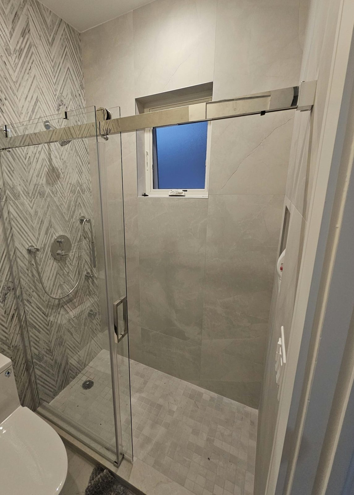 Frameless sliding glass shower door slid open in front of the fixed panel in a Borough Park, Brooklyn bathroom