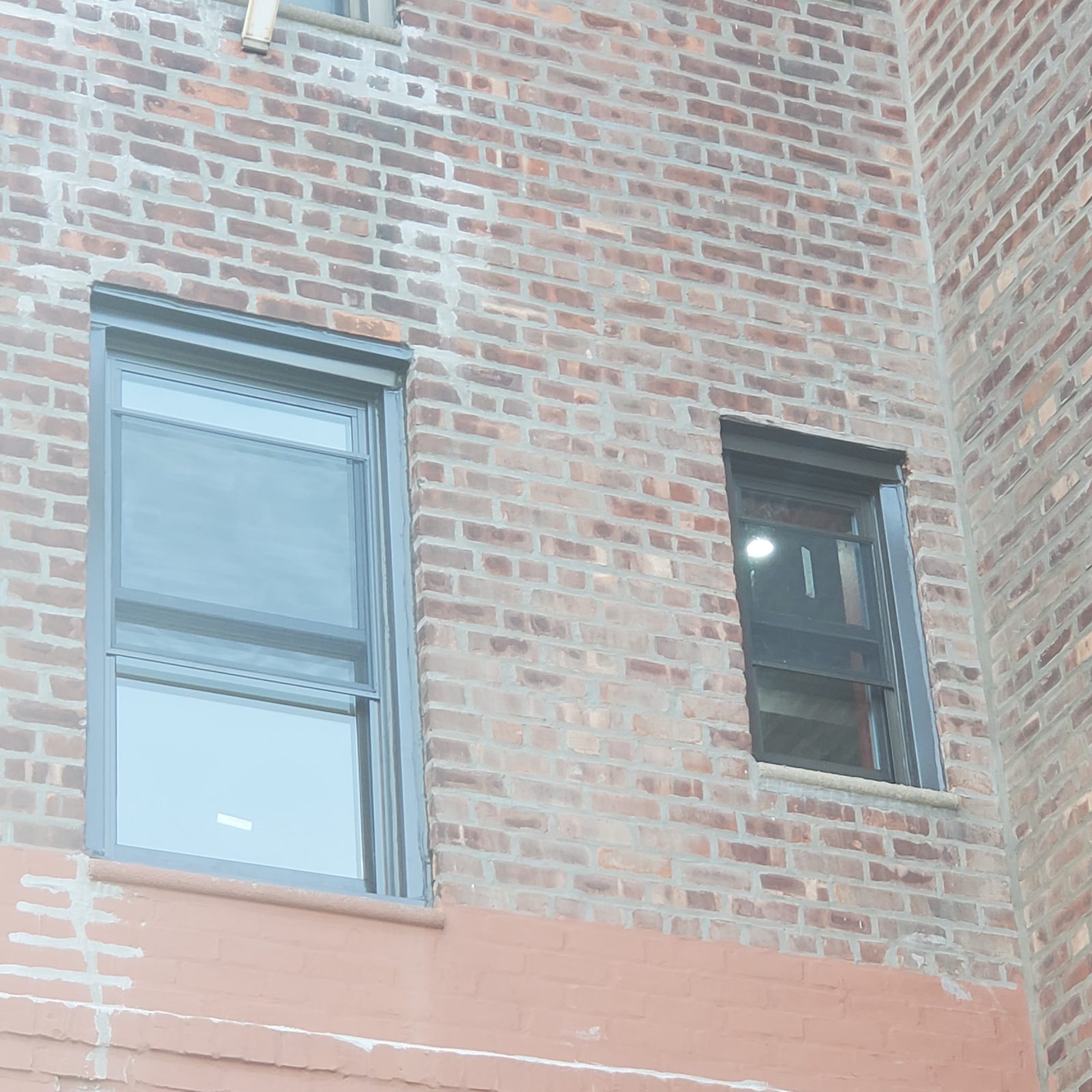 Two double-hung replacement windows in adjoining brick walls, Brighton Beach, Brooklyn