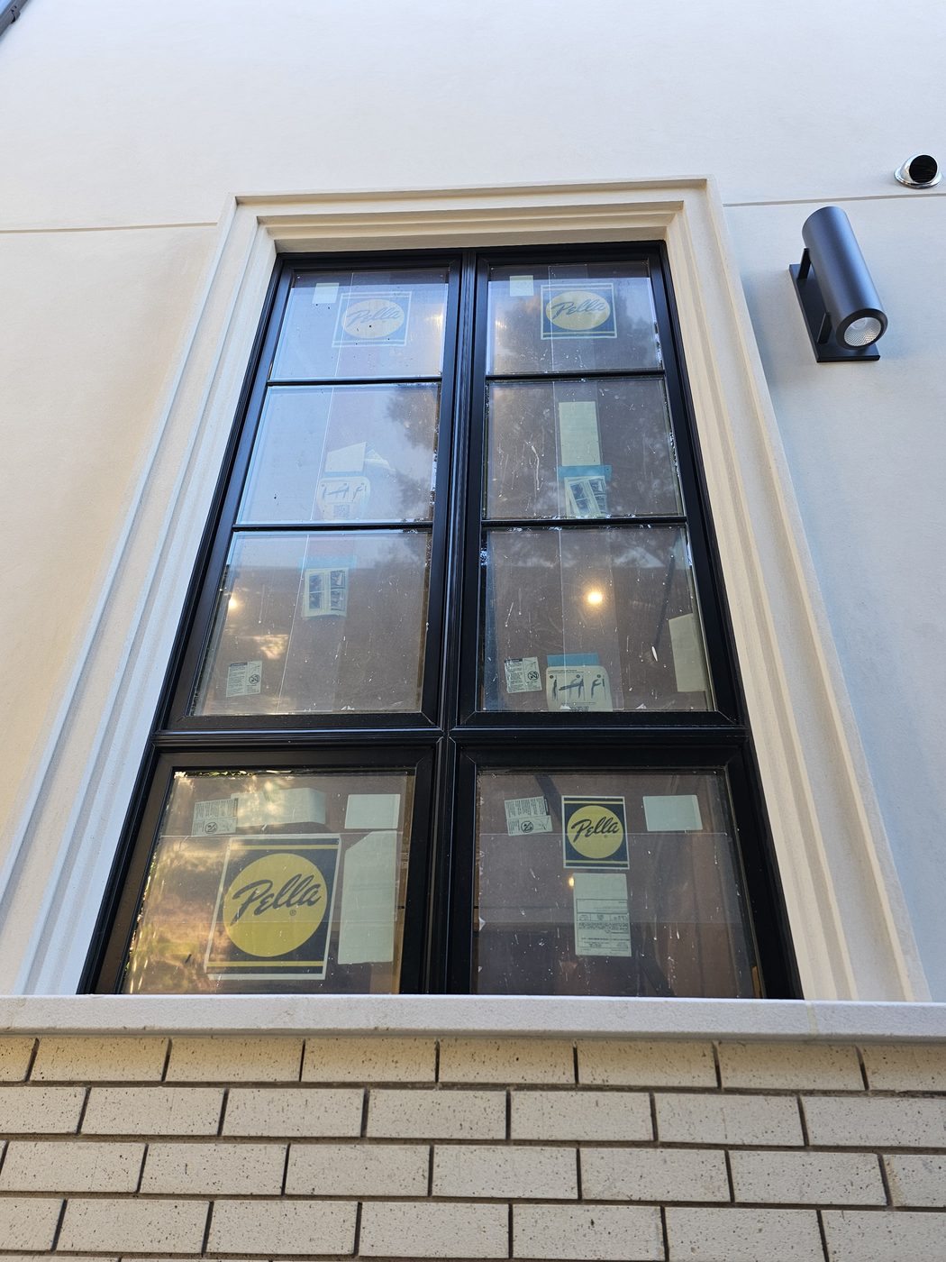 Tall paired Pella casement window with divided lites and black frame in a cast-stone surround, Manhattan Beach