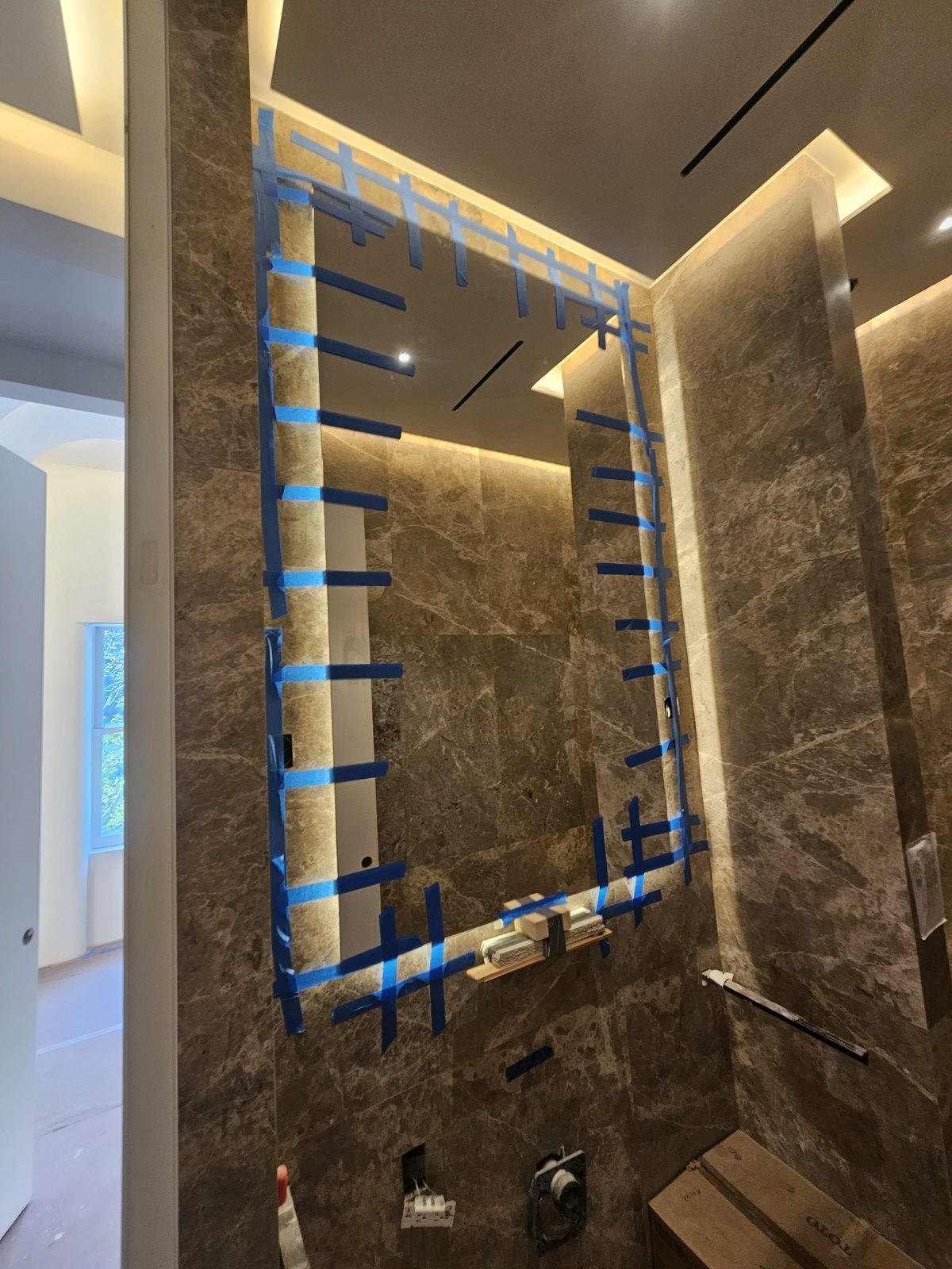 Backlit low-iron mirror with a soft LED halo on grey marble in a Manhattan bathroom on East 18th Street