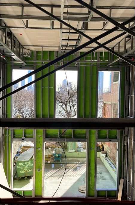Two-storey wall of window openings in steel framing during construction at the Embassy of Tunisia, New York, with the Manhattan skyline beyond