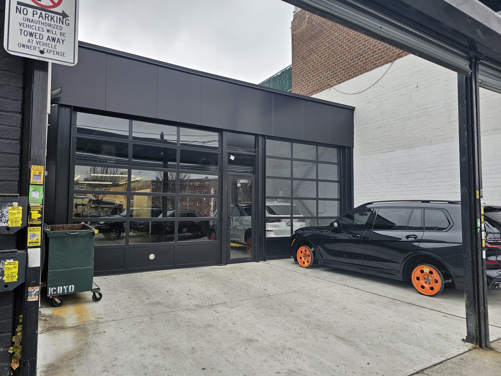 New black storefront and aluminum composite panel facade with a commercial glass door and transom at the Gran Prix auto business on Flatbush Avenue, Brooklyn