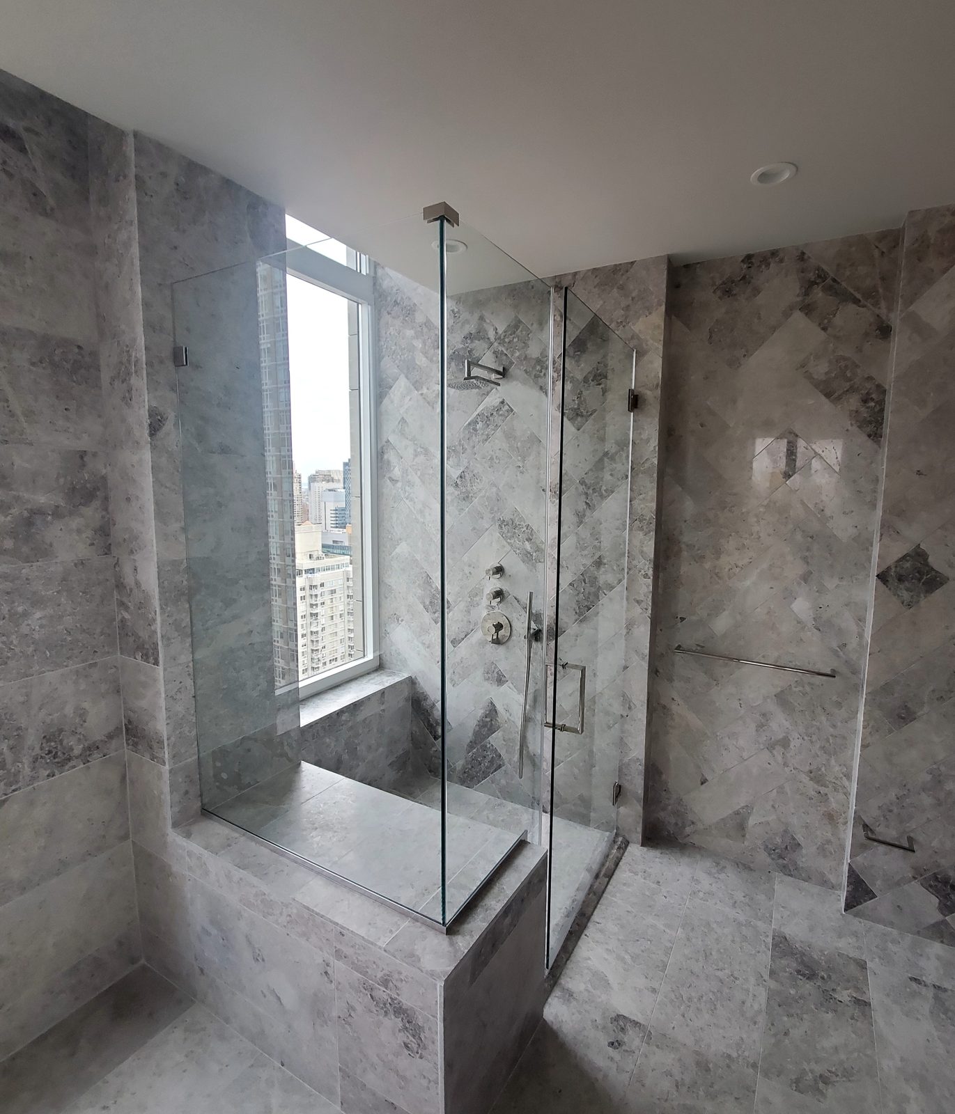 Frameless corner shower enclosure in extra clear low-iron glass with a panel on the marble bench, apartment bathroom in Lenox Hill, Manhattan