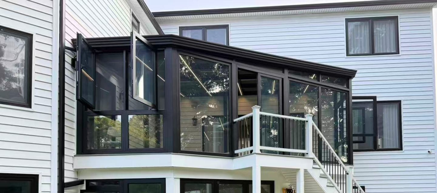 Finished custom sunroom in black aluminum and glass on the raised deck of a white house in Manalapan, NJ, with windows open