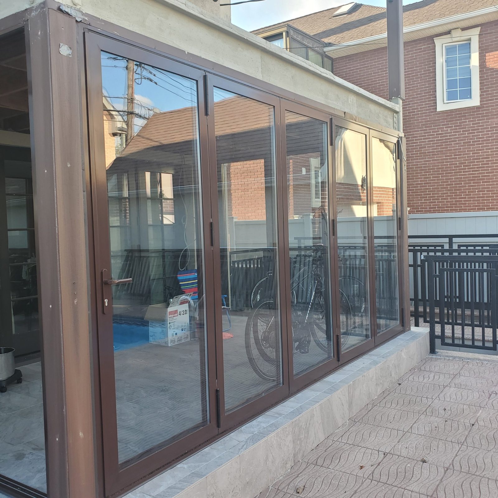Five-panel brown aluminum bifold door on the long side of a sunroom in Manhattan Beach, Brooklyn