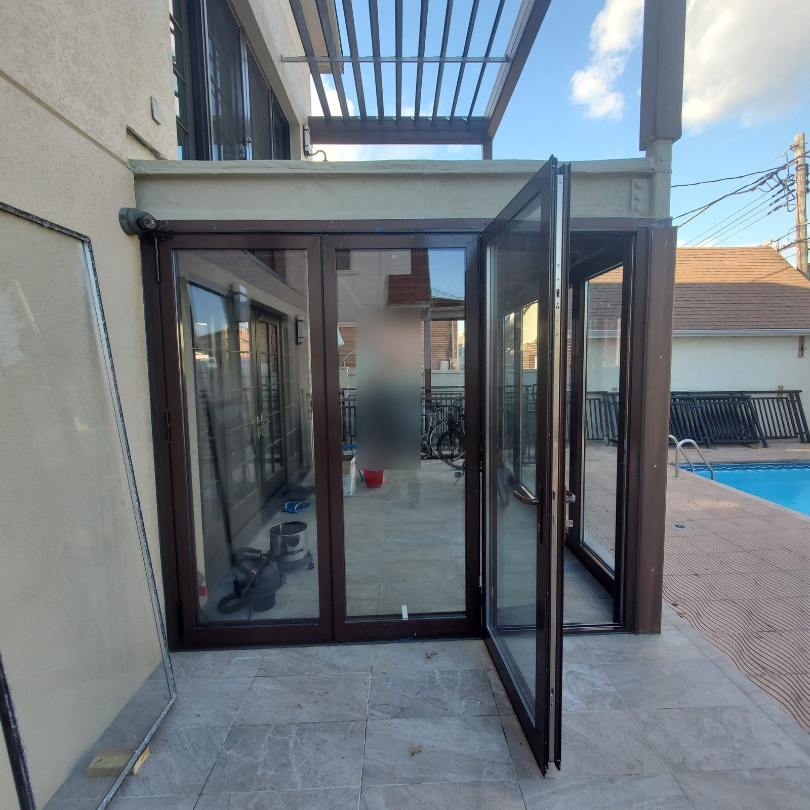 Three-panel bifold door with the end panel open on a sunroom beside a pool in Manhattan Beach, Brooklyn