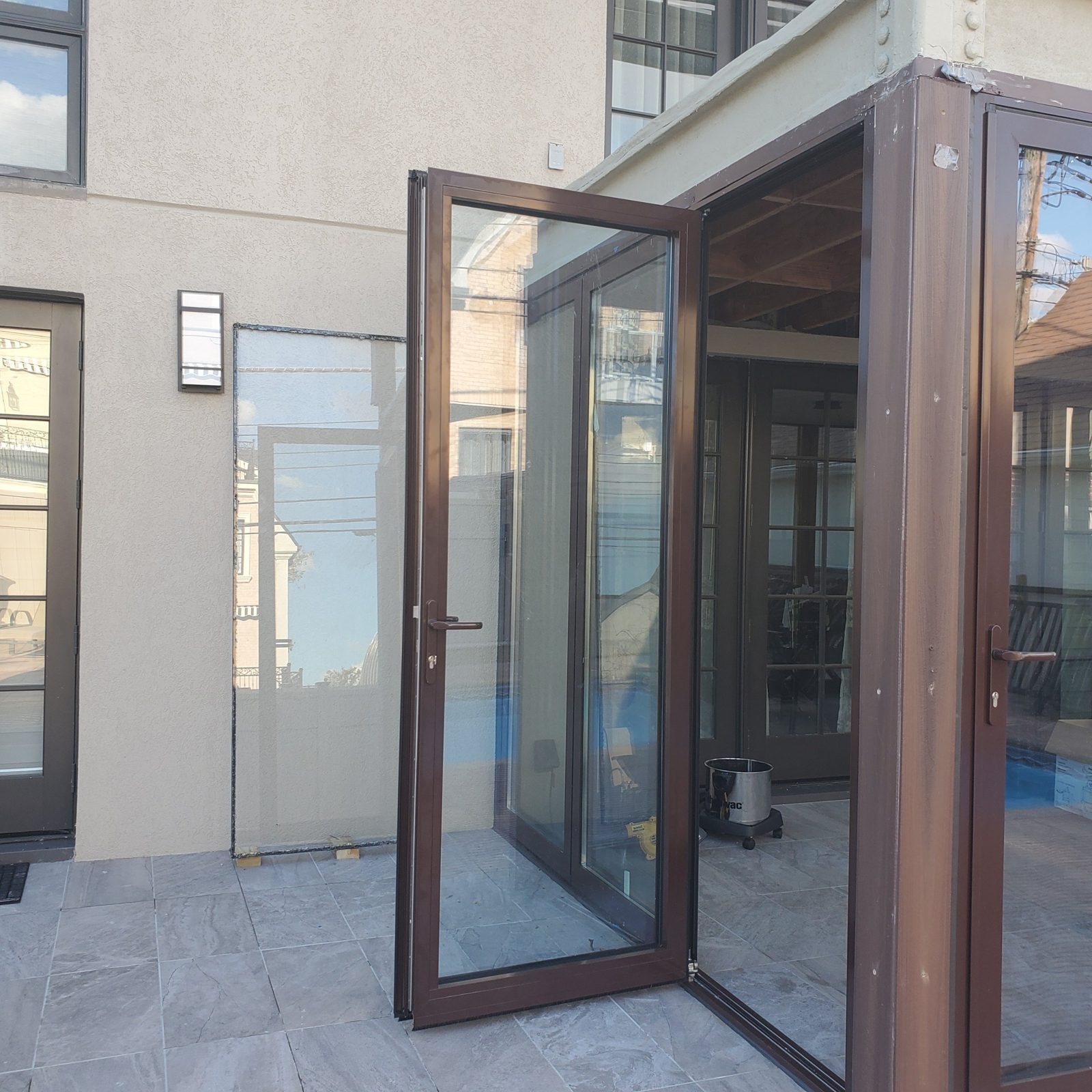 Open bifold door panel with lever handle and key lock on a sunroom in Manhattan Beach, Brooklyn