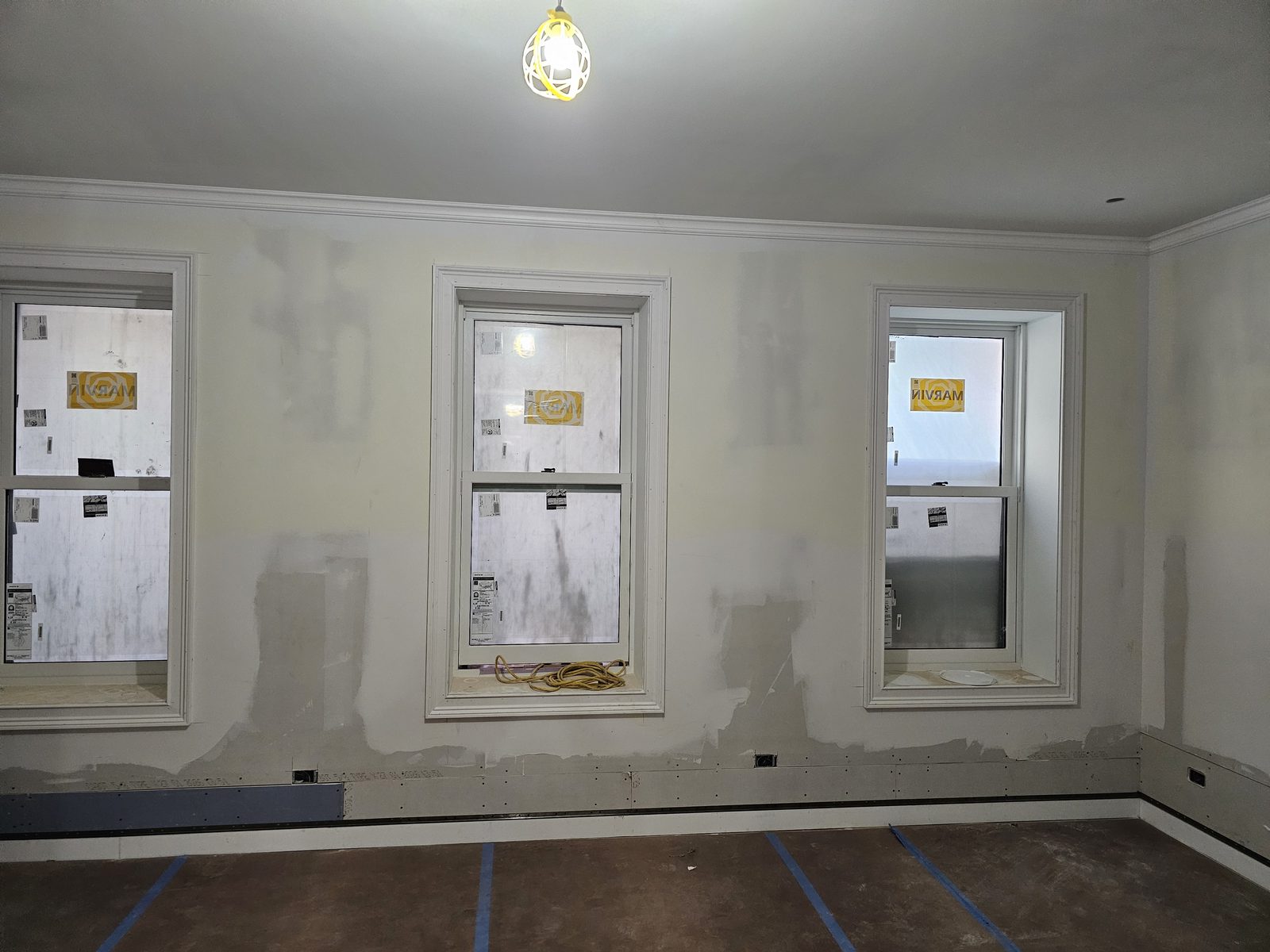 Three Marvin Ultimate wood double-hung windows with white casings in a room under construction on East 70th Street