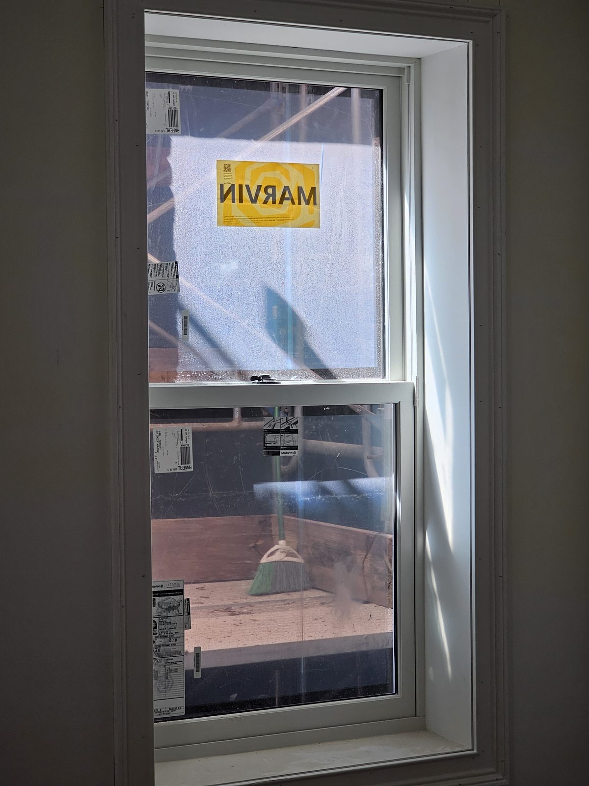 Single Marvin Ultimate double-hung window with white interior in a deep reveal, scaffold visible outside