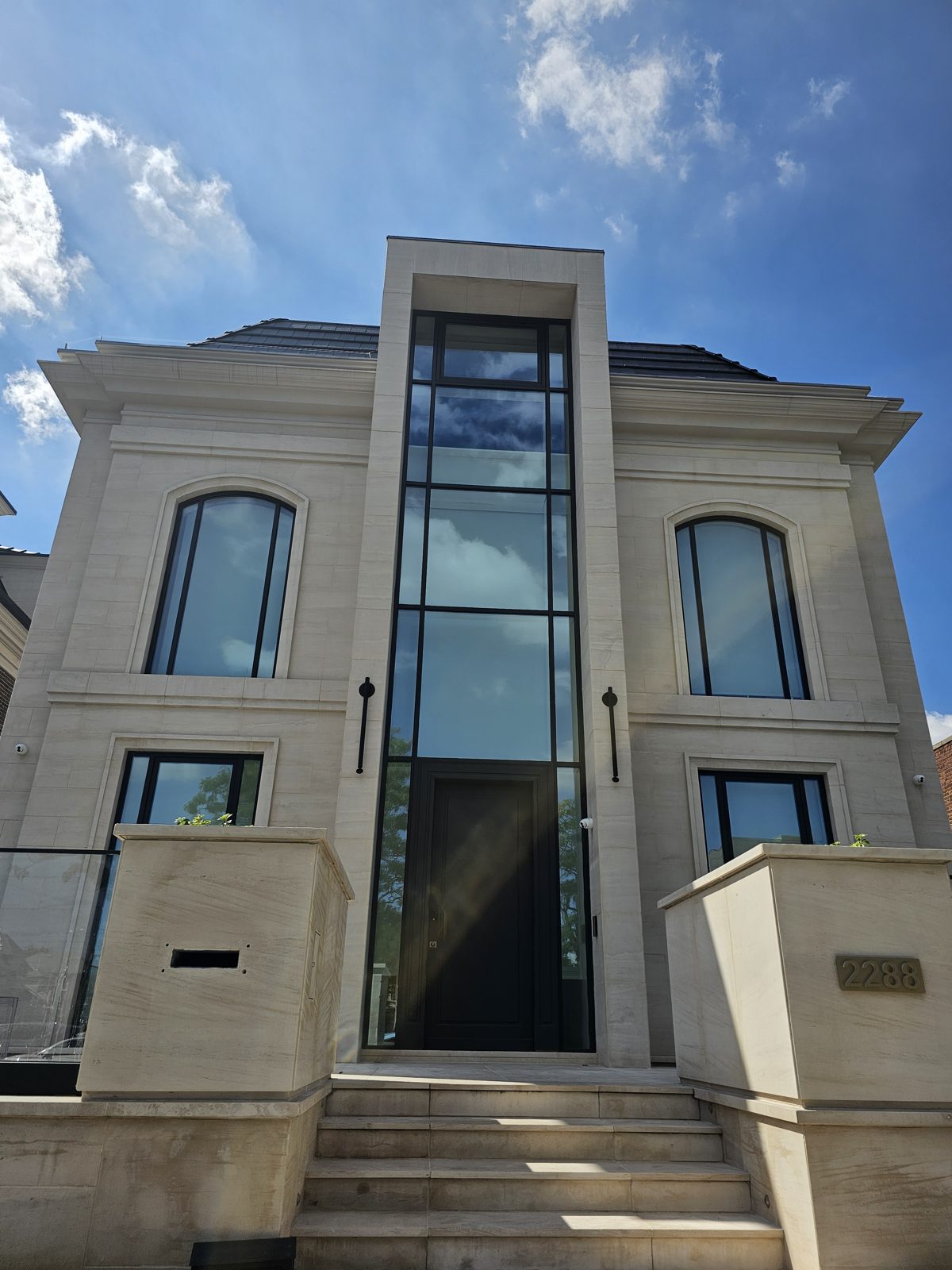 Two-storey Reynaers aluminum curtain wall entry slot in a limestone facade, Gravesend, Brooklyn