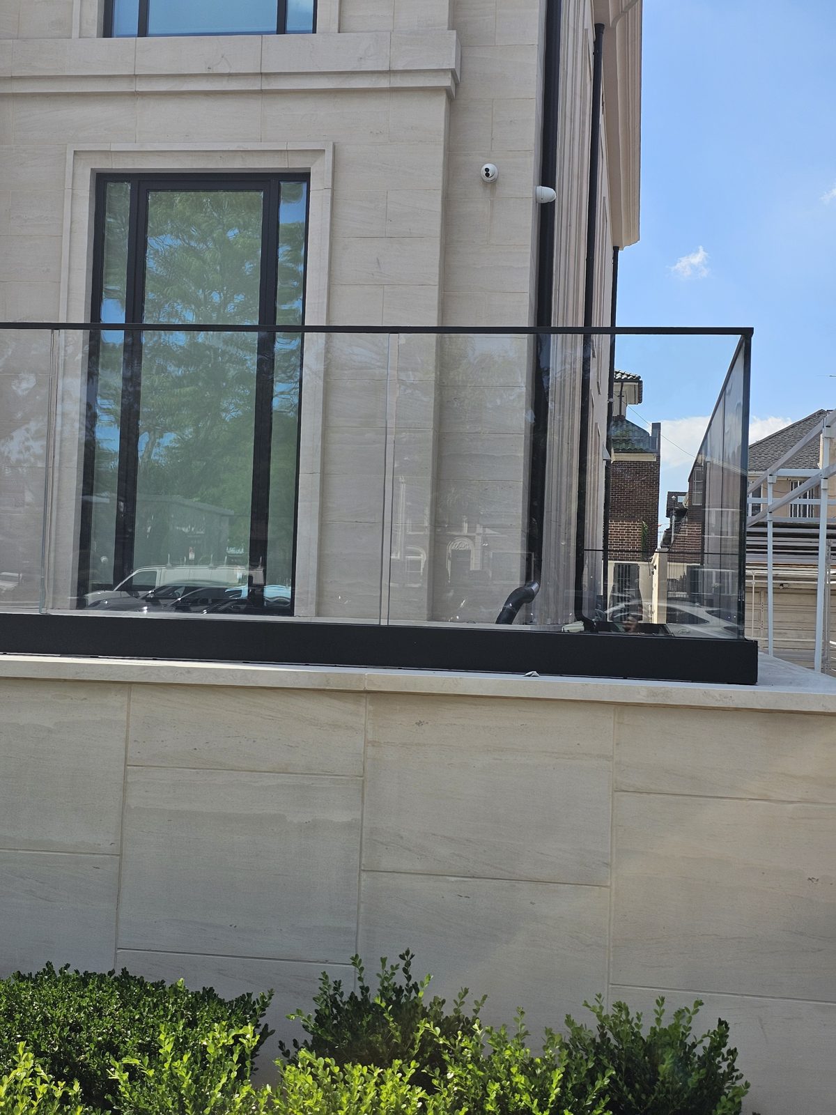 Terrace glass railing with black posts and tall Reynaers windows behind