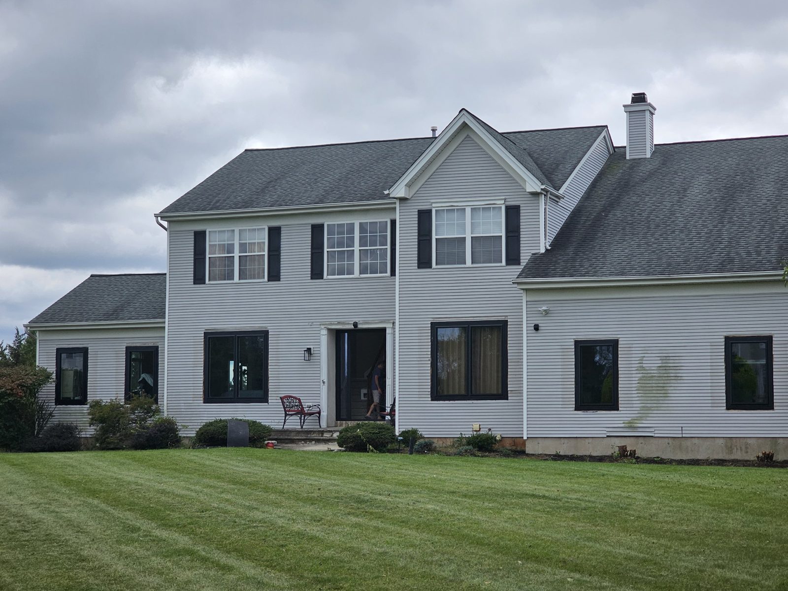 Front of a two-storey white colonial house in Somerset NJ with new black aluminium ground-floor windows and a black entry door, original white double-hung windows above