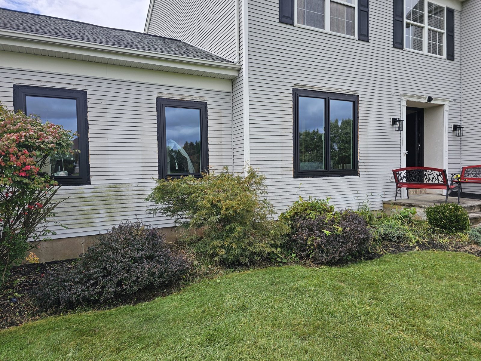 Black aluminium single and paired windows in white vinyl siding beside the front entrance of a colonial house in Somerset NJ