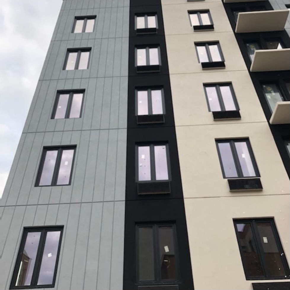 Side facade of The Elston with single and paired black Aluplast windows set in grey composite panels
